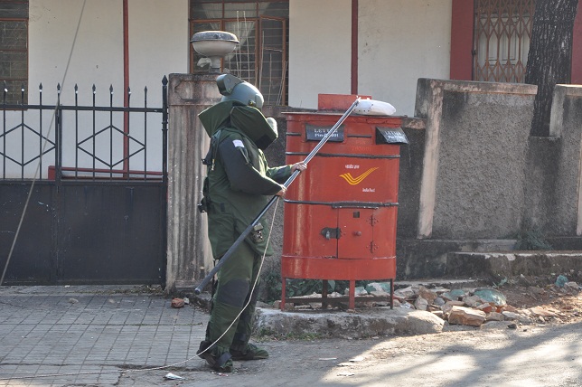 A bomb squad member trying to fish the oarcel from atop the post box. TM pix